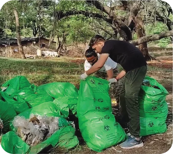 Volunteers working together to collect litter into a large green bag