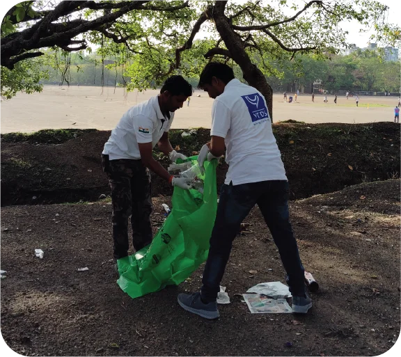 Volunteers picking up waste in an open area during a cleanup activity