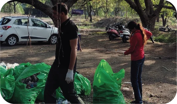 Two volunteers collecting trash and placing it into a green waste bag