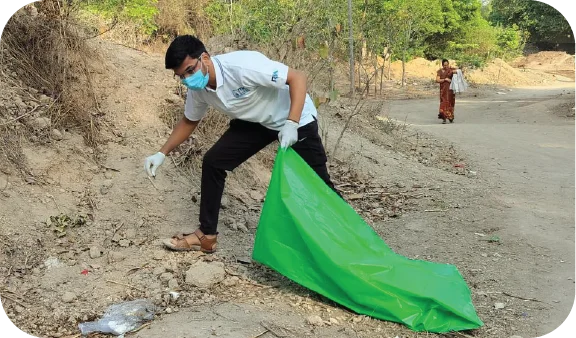 Volunteer picking up waste along a roadside during a cleanup drive
