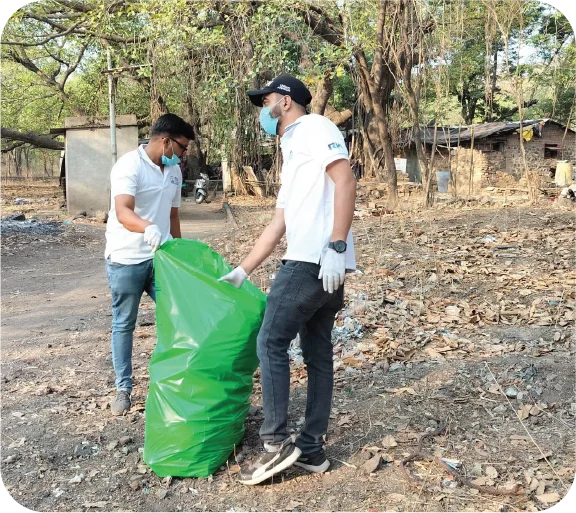 Volunteer collecting litter in a dry forest area using a garbage bag